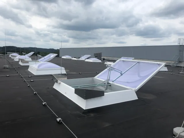 Geöffnete Lichtkuppel einer natürlichen Rauchabzugsanlage (NRA) auf einem Industriedach