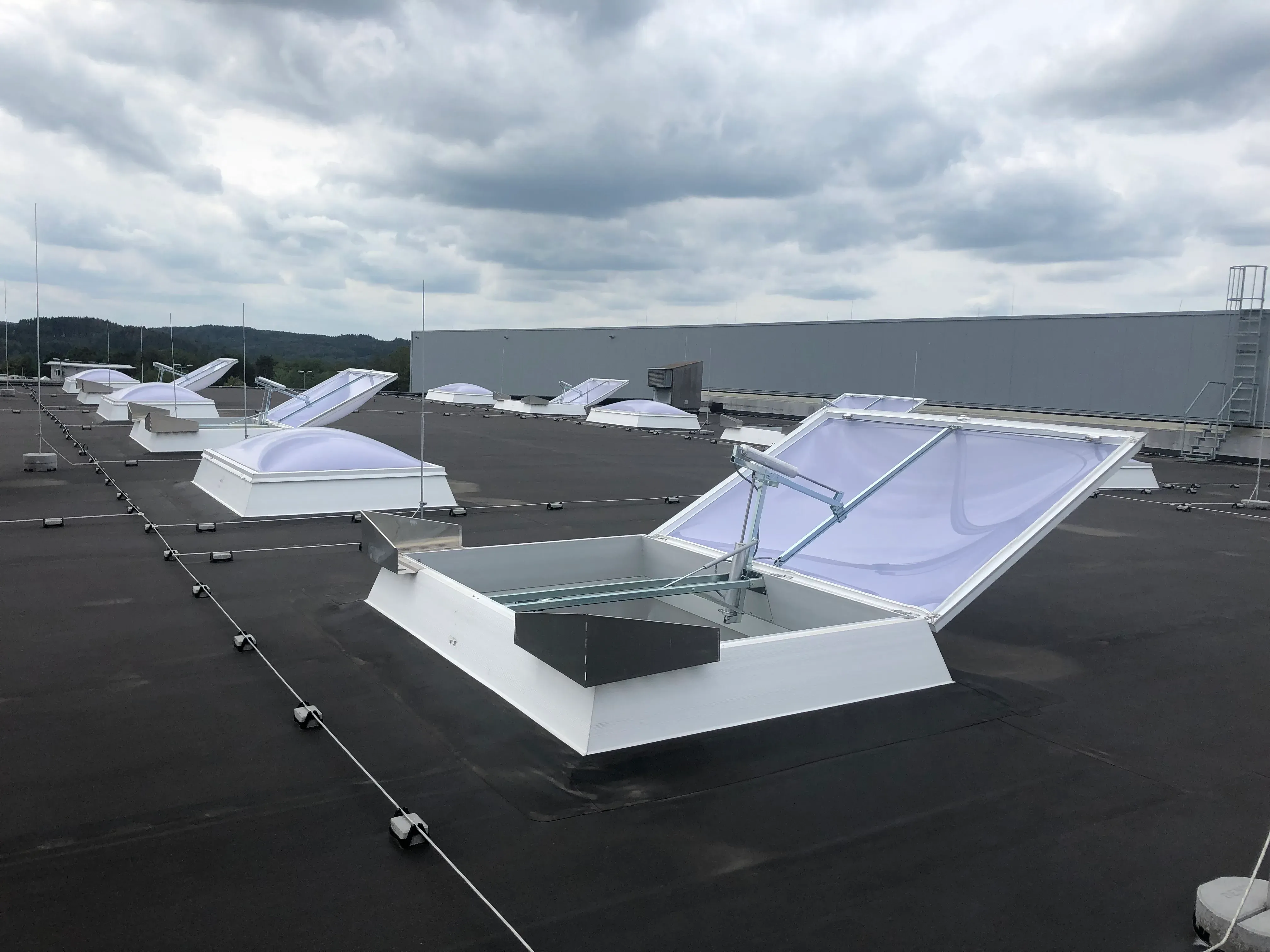 Geöffnete Rauch- und Wärmeabzugsanlage (RWA) mit Lichtkuppeln auf einem Industriedach in NRW