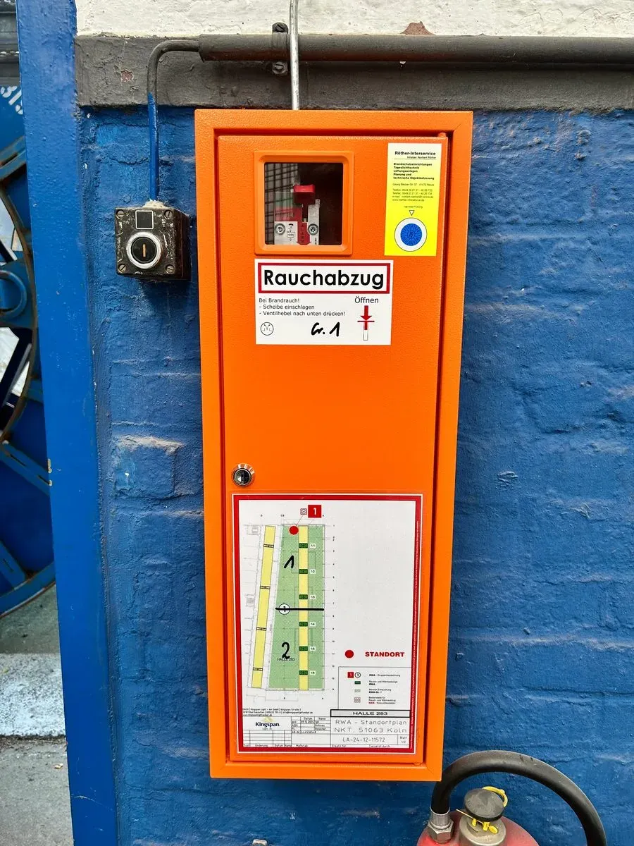 RWA-Handauslöser mit Röther-Interservice Prüfplakette an einer Industriehalle